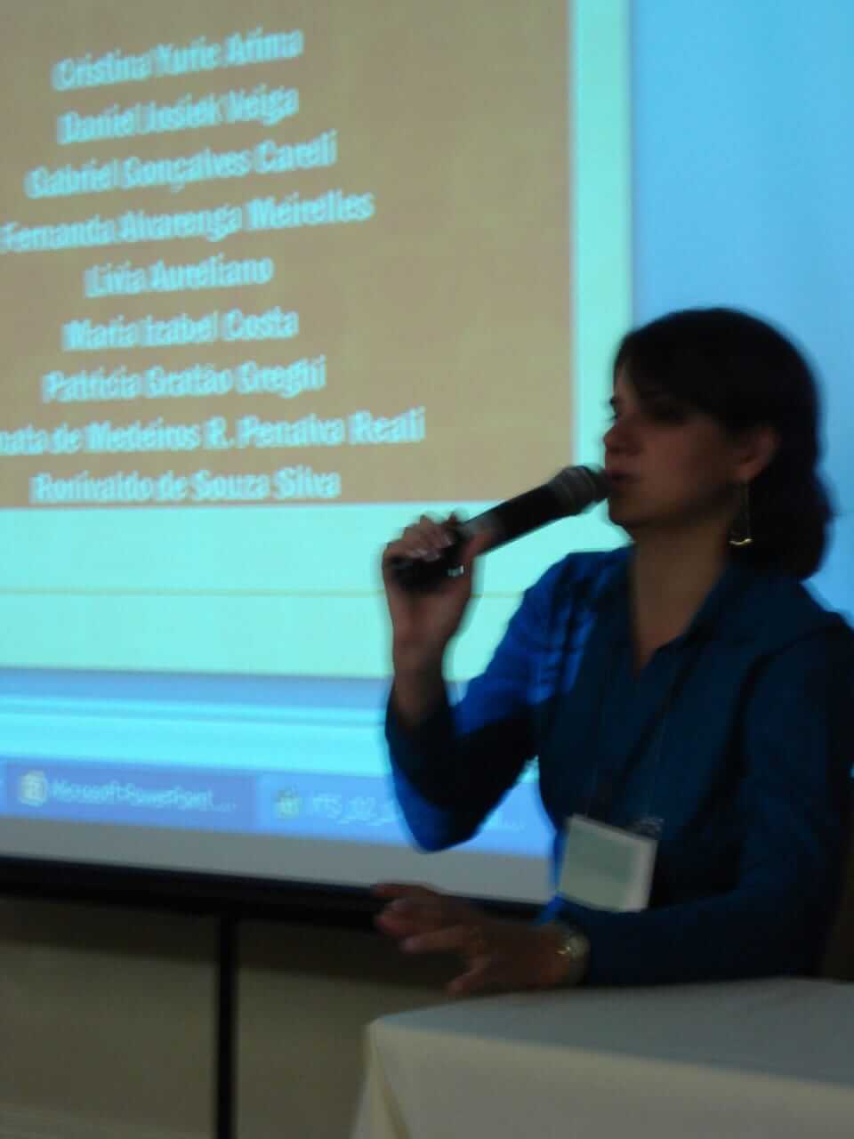 Lívia falando ao microfone em congresso da ABPMC